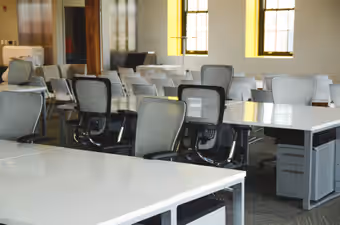 Plateau de bureaux meublé de tables blanches et de sièges, avant enlèvement du mobilier