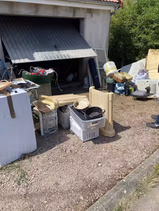 Électroménager, meubles et cartons sortis devant un garage ouvert, prêts au chargement